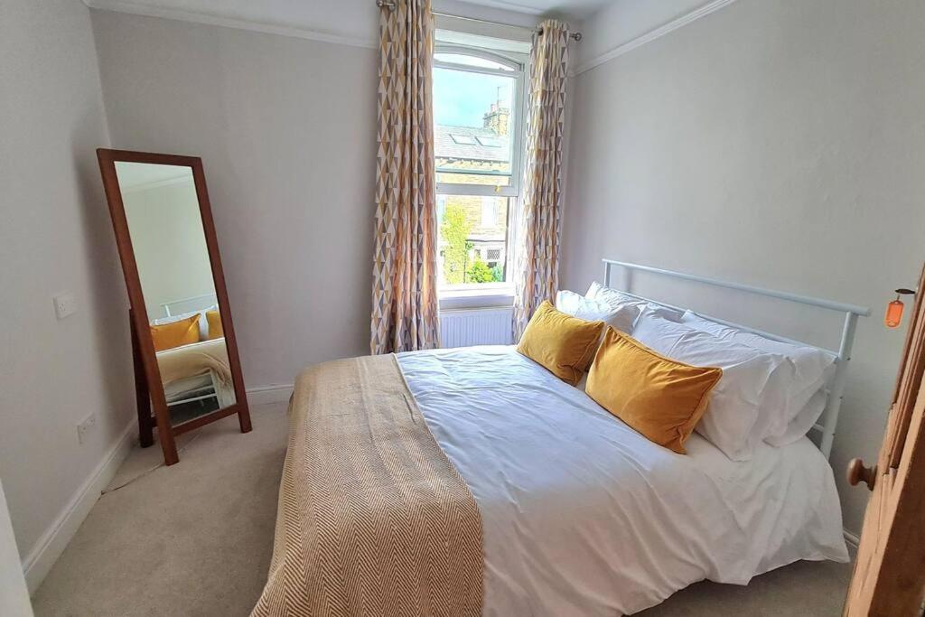 una camera da letto con letto, cuscini gialli e specchio di Brylie House, Large Central family home a Skipton