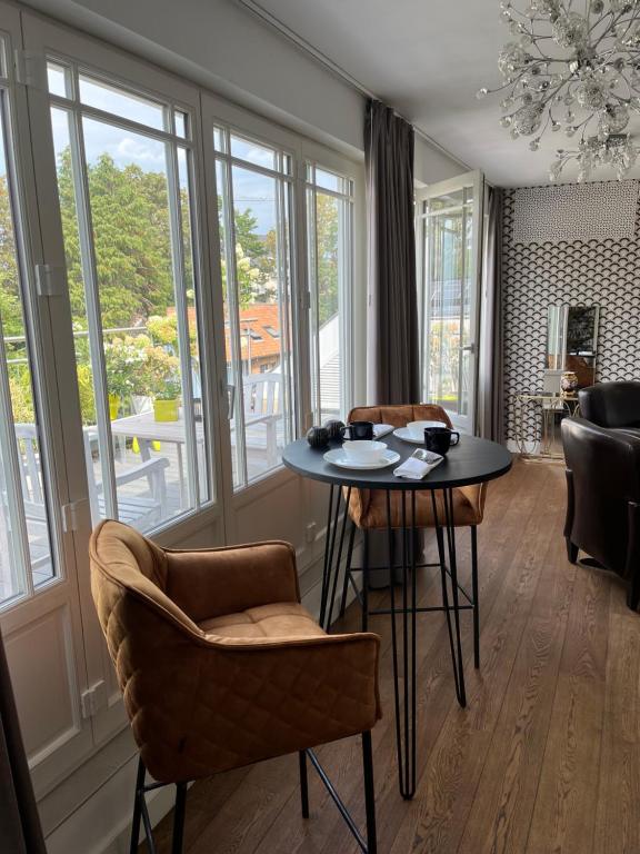 a living room with a table and chairs and windows at Rooftop terrace suite in Heist-op-den-Berg