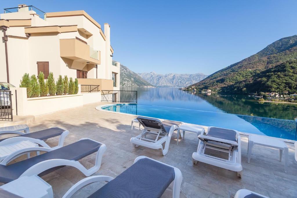 a swimming pool with chairs and a view of the water at Keystone Apartments in Donji Morinj