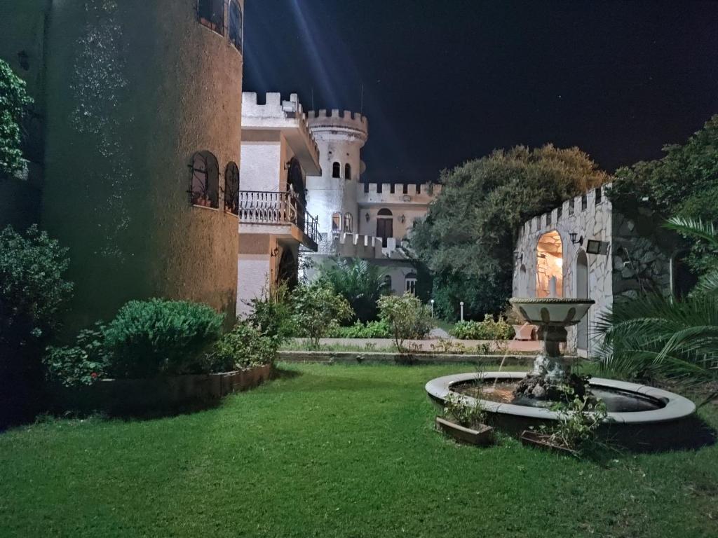 un castillo de noche con una fuente en el patio en Castle By The Sea, en Artemida