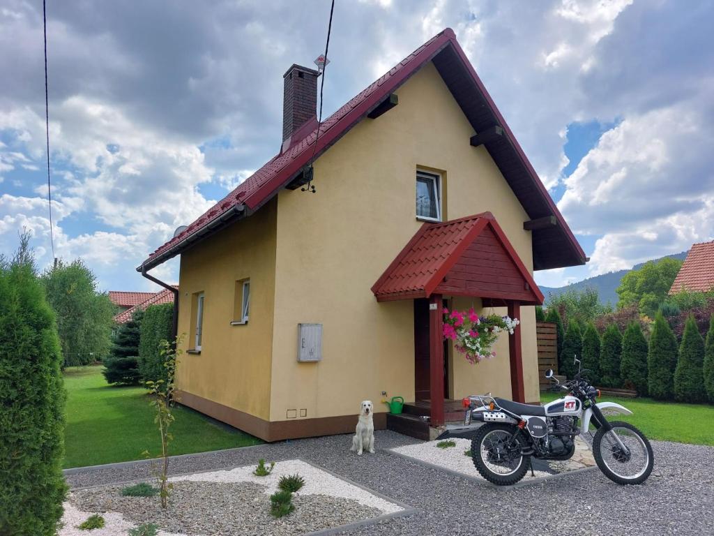 a motorcycle parked in front of a small house at Uroczy Domek z Kominkiem in Lipowa