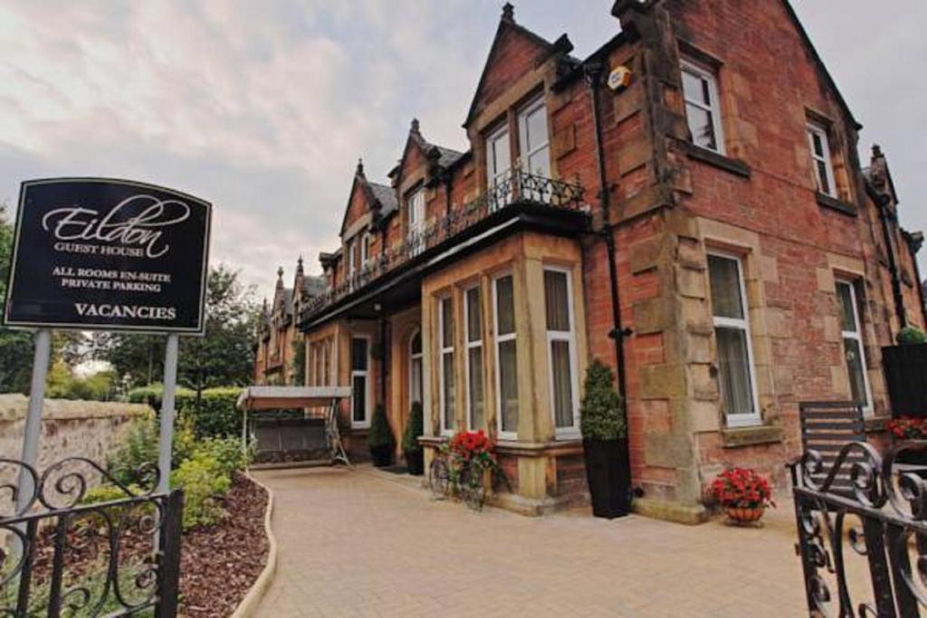 un vecchio edificio di mattoni con un cartello di fronte di Eildon Guest House a Inverness