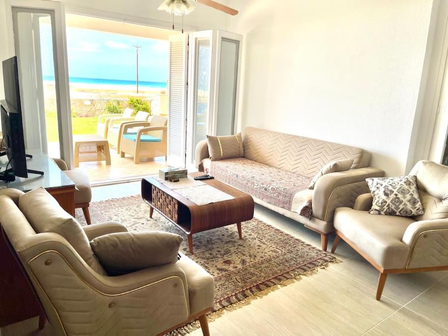 uma sala de estar com um sofá e uma mesa em Stunning Beachfront Villa on North Coast Mediterranean em Dawwār Abū Maḩrūs