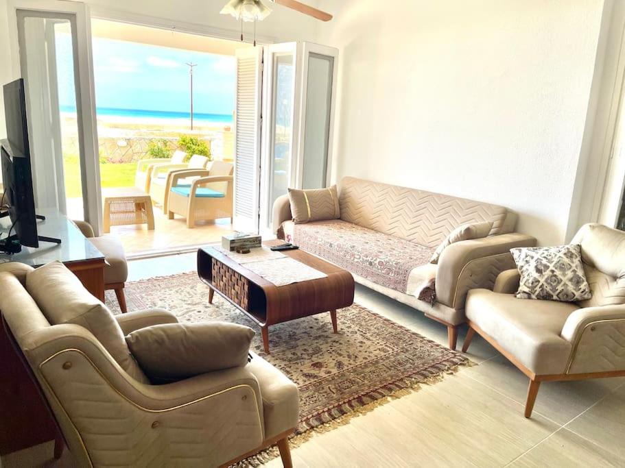 Stunning Beachfront Villa on North Coast Mediterranean في Dawwār Abū Maḩrūs: غرفة معيشة مع أريكة وطاولة