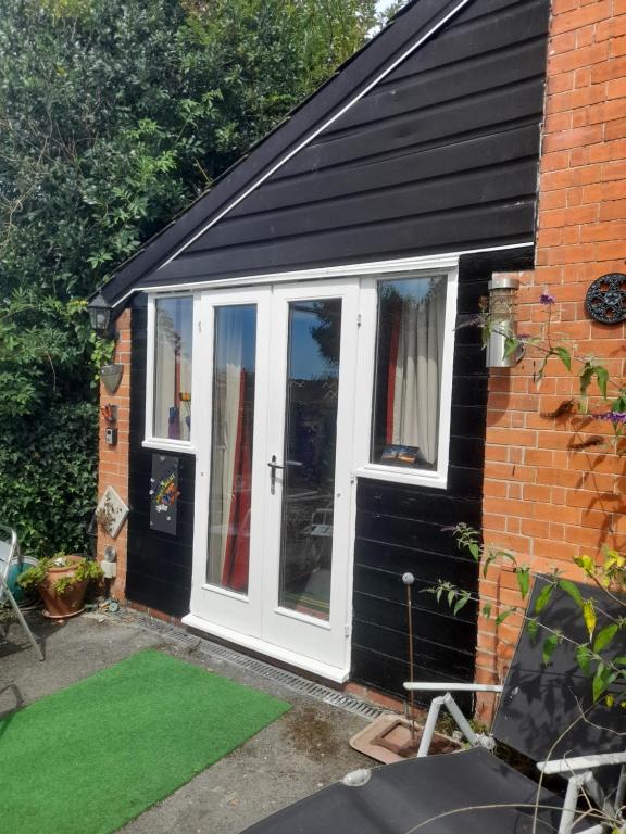 a white door on a house with a green lawn at Janet Hale Studios, Garden Apartment in Glastonbury