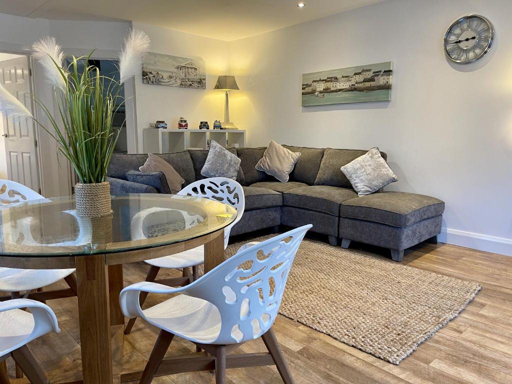 uma sala de estar com um sofá, uma mesa e cadeiras em Relaxing 2 Bedroom Garden Cottage em Coleraine