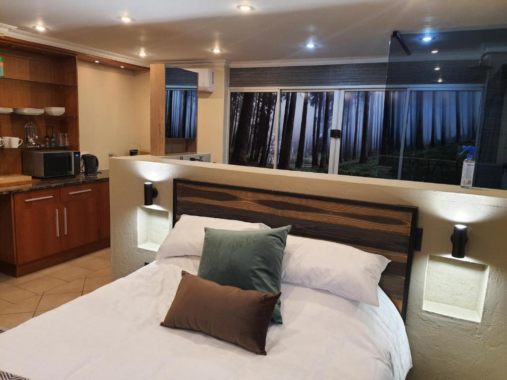 a bedroom with a large bed and a kitchen at Bikkurim Inn in Nelspruit