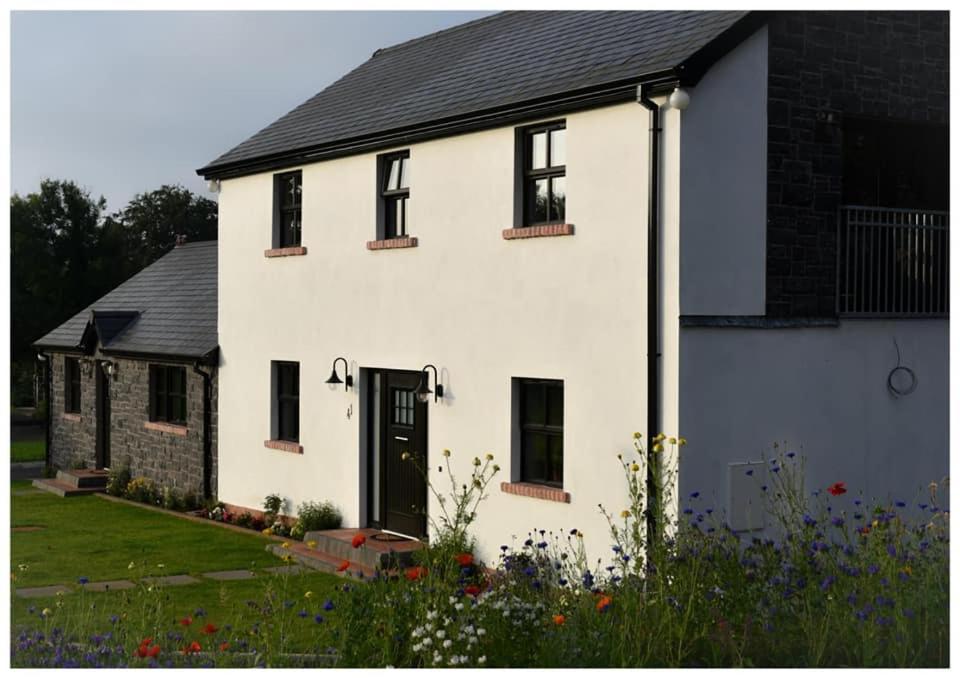 uma casa branca com uma porta preta e algumas flores em Mill House em Portglenone