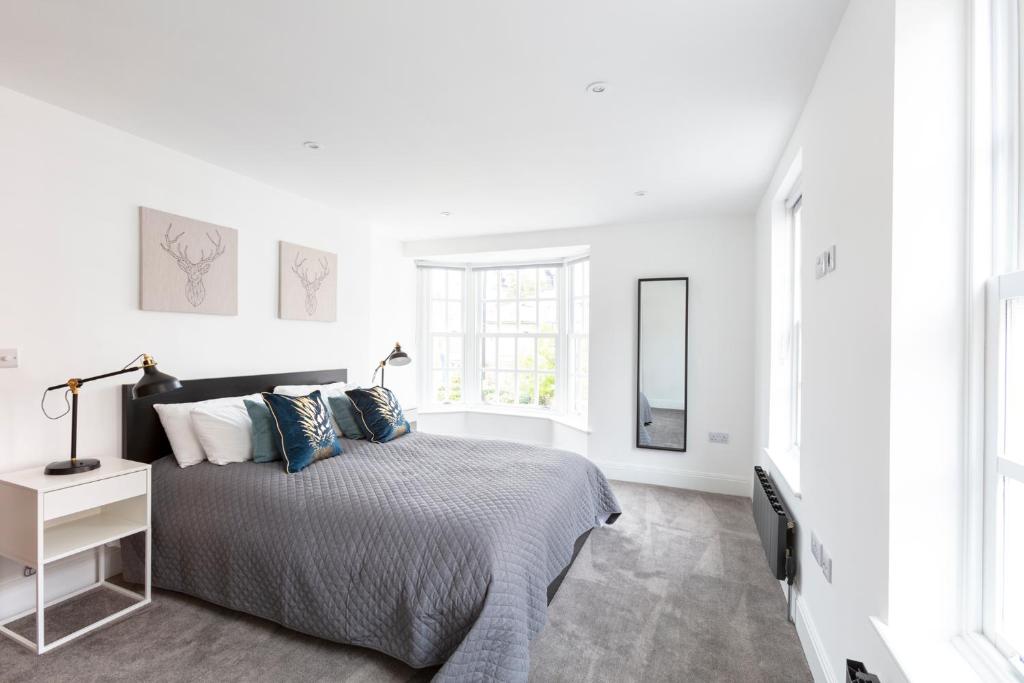 a white bedroom with a bed and a mirror at Hampden Apartments - The Louis in Eton