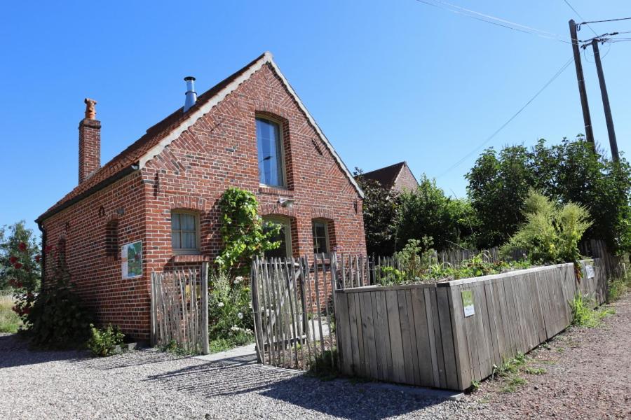 an old brick house with a wooden fence at Les Jardins d'Olus in Wandignies-Hamage
