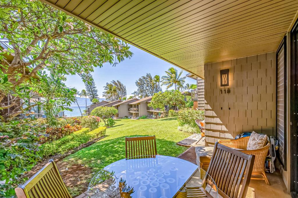 eine Terrasse mit einem Tisch und Stühlen sowie einem Hof in der Unterkunft Polynesian Shores 118 in Kahana