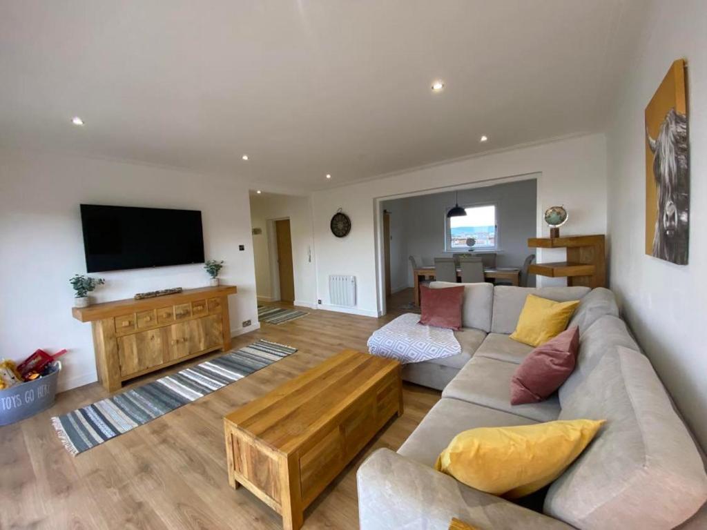 a living room with a couch and a flat screen tv at Beachfront Penthouse, Largs in Largs