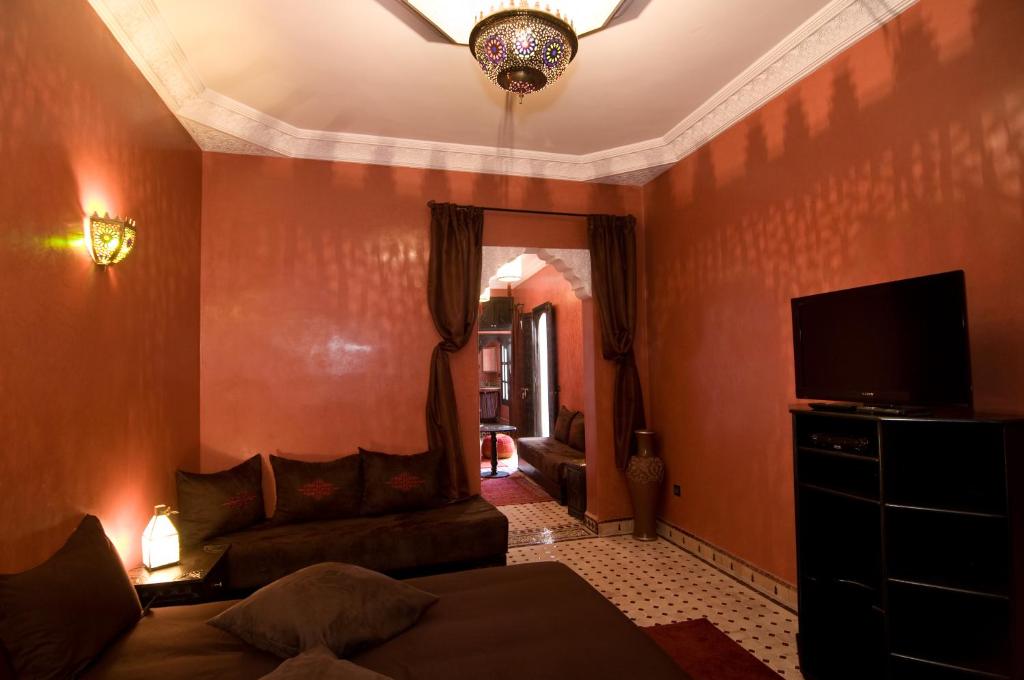 een woonkamer met een bank en een flatscreen-tv bij RIAD N° 16 in Marrakesh