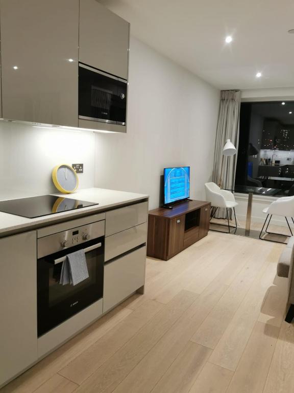 a kitchen with a stove top oven next to a living room at Comfy 1 bed studio 1 minute from Train station in London