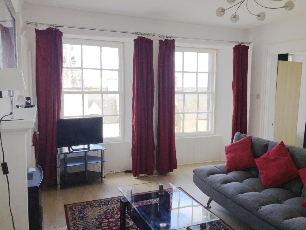 Beautiful 2 Bed Serviced Apartment in Dunbar في دنبار: غرفة معيشة مع ستائر حمراء وأريكة
