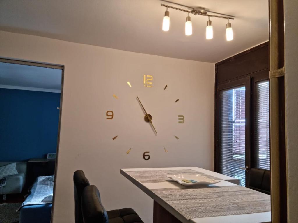 un orologio su una parete in una stanza con tavolo di Kingston a Pirot