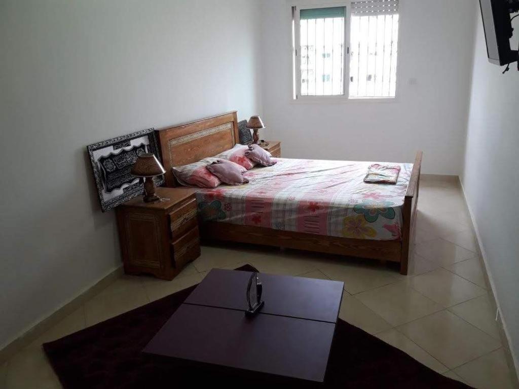 Un dormitorio con una cama y una mesa. en Appt à plage sidi Rahal, en Sidi Rahal