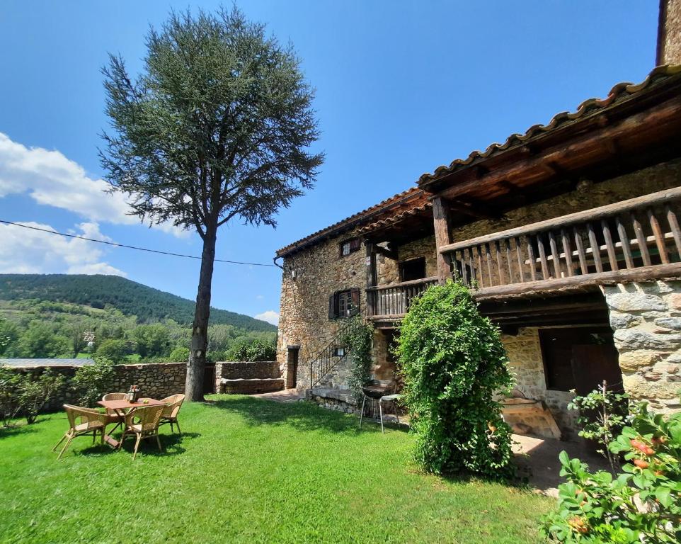 ein Haus mit einem Tisch und einem Baum im Hof in der Unterkunft L' Antiga Cadarnera in Bor