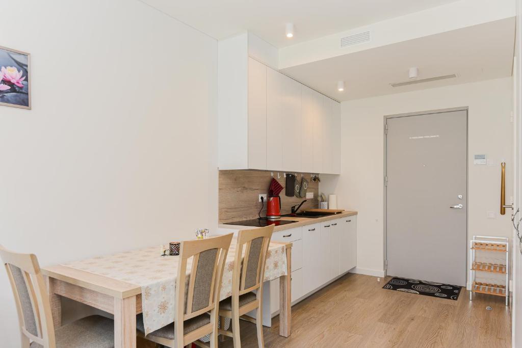 a white kitchen with a wooden table and chairs at White Forest in Juodkrantė