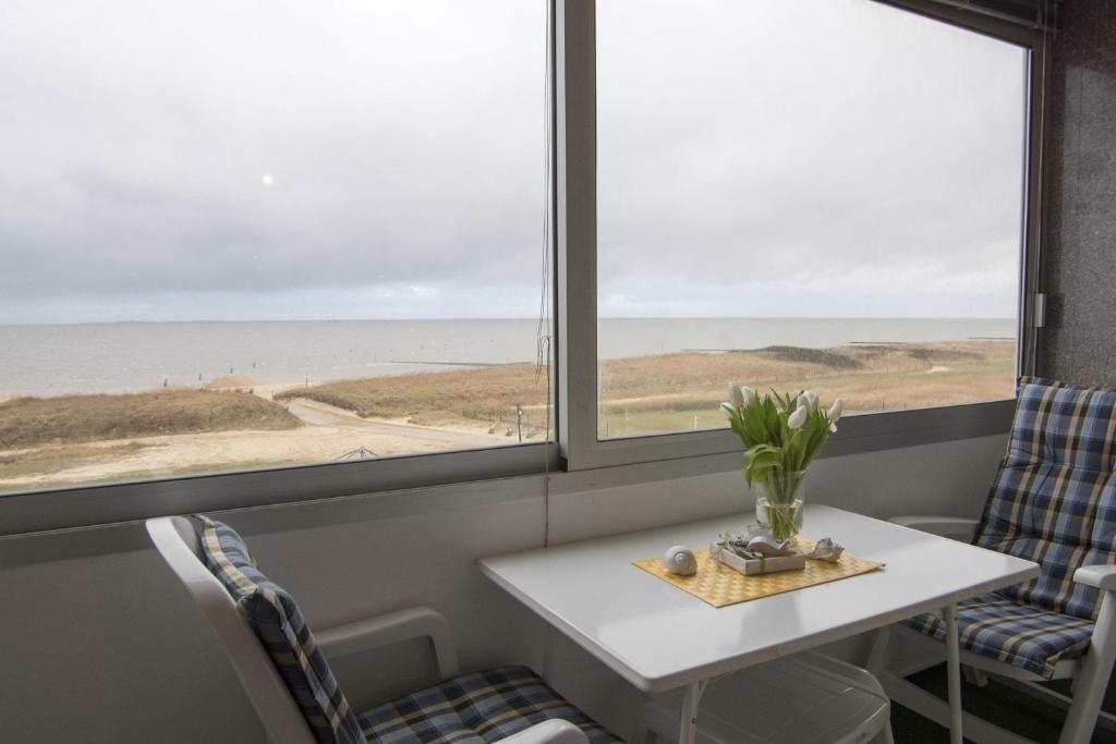 una mesa y sillas en una habitación con vistas al océano en Am-Sahlenburger-Strand-1-Whg-15, en Cuxhaven