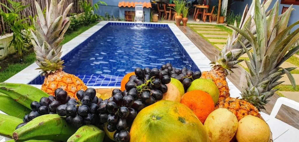 a pile of fruit sitting next to a swimming pool at Pousada La Vita in São Miguel dos Milagres