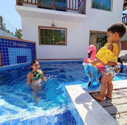 two children are playing in a swimming pool at Aconchego dos Netos 2 - PRAIA DOS 3 COQUEIROS in Marau