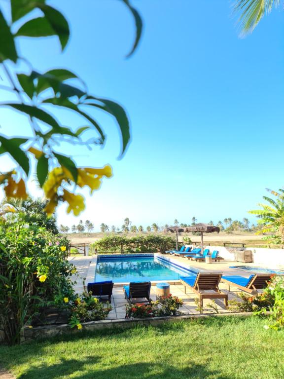 una piscina en un patio con sillas alrededor en Pousada Vila Bacana, en São Miguel do Gostoso