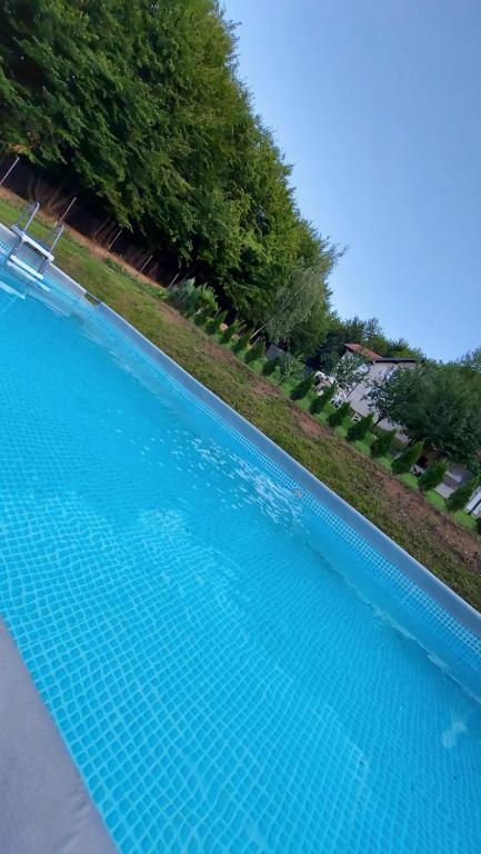 uma grande piscina azul com árvores ao fundo em Mala farma Nani em Visoko