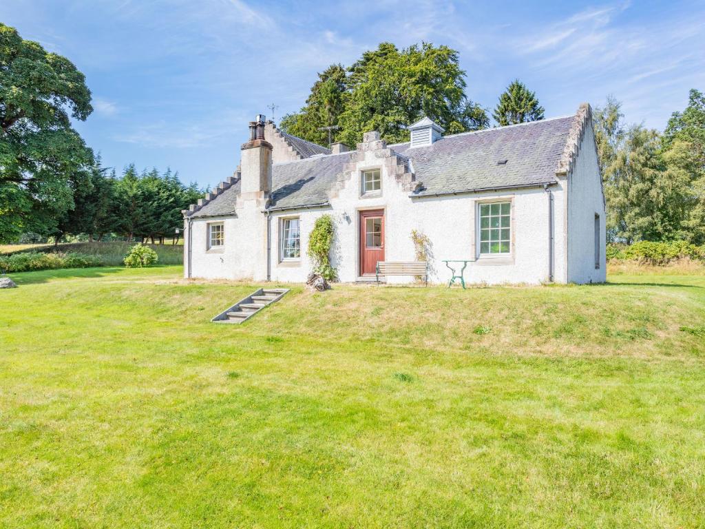 a white house with a large grassy yard at The Old Laundry in Grantown on Spey