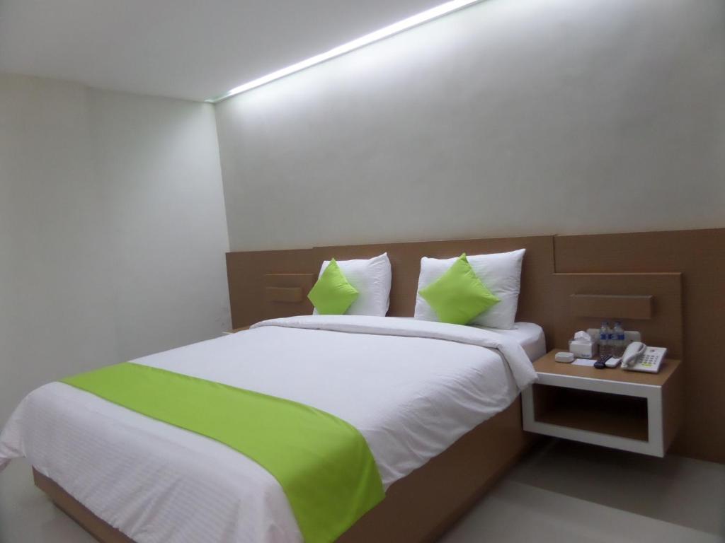 a bedroom with a large bed with green pillows at Shinta Guesthouse in Malang