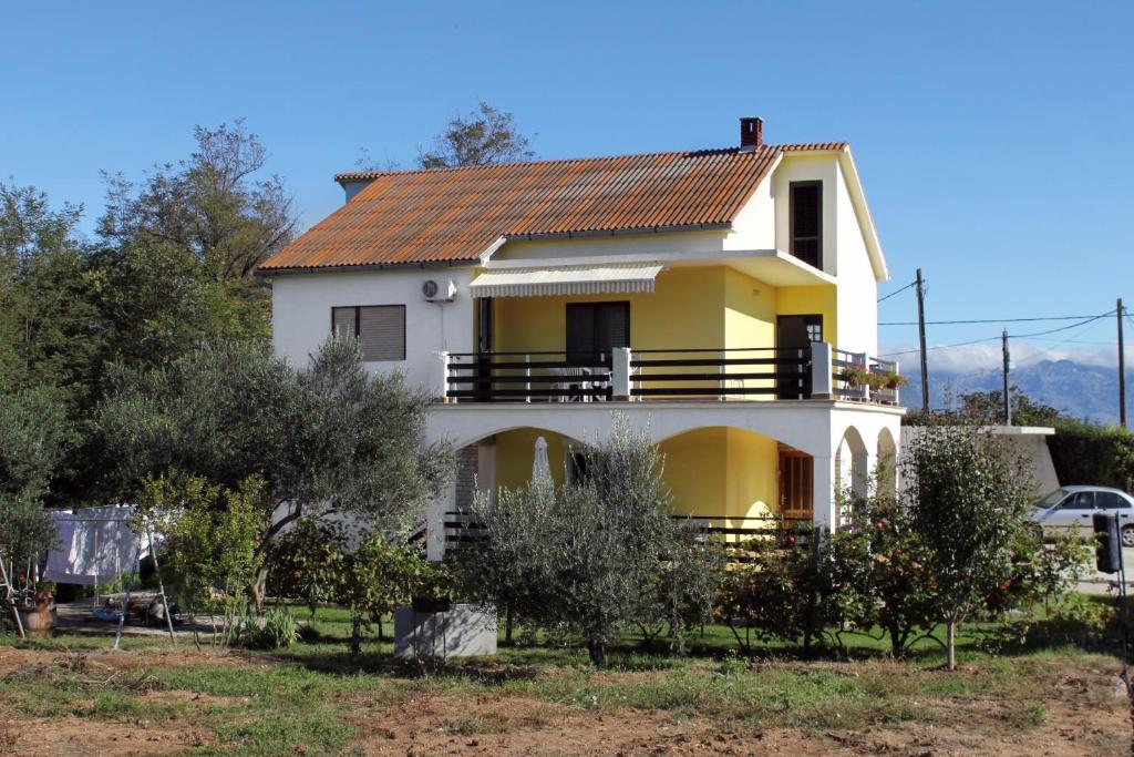uma casa amarela e branca com árvores em frente em Apartments with a parking space Privlaka, Zadar - 667 em Privlaka