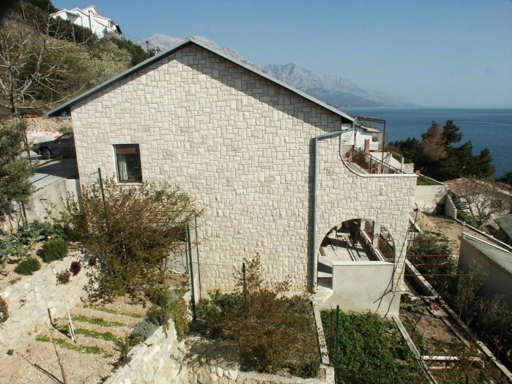 un bâtiment en briques blanches avec une arche sur une colline dans l'établissement Apartments by the sea Pisak, Omis - 658, à Mimice