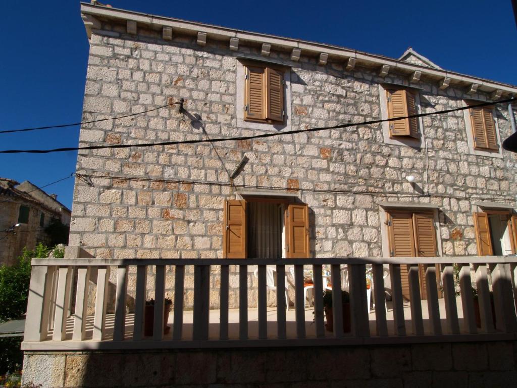 an old stone house with a wooden fence at Apartments by the sea Sutivan, Brac - 719 in Sutivan