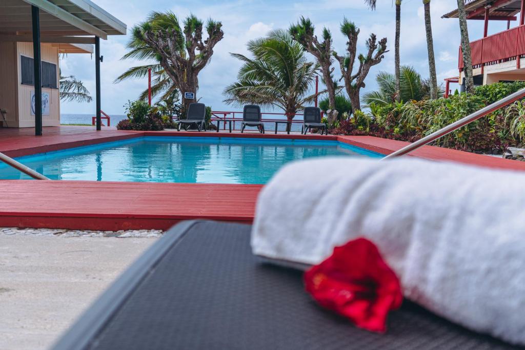Kiikii Inn & Suites في راروتونغا: وضع رباط احمر على سرير بجانب مسبح