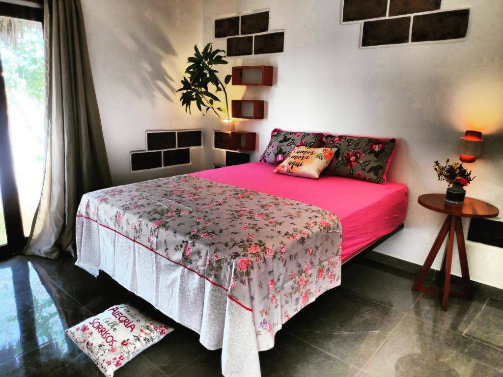 1 dormitorio con 1 cama con colcha rosa en Anacardium, en Canoa Quebrada