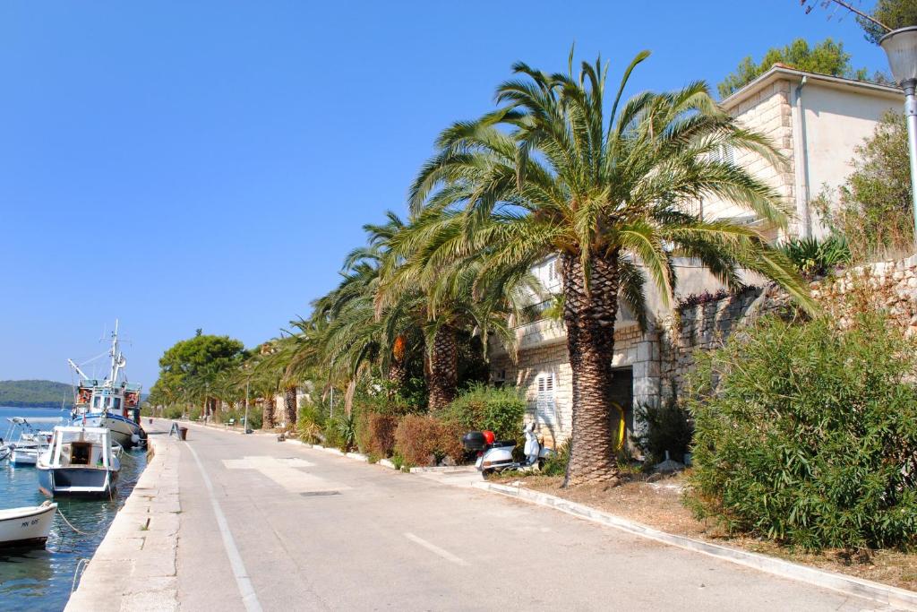 a street with palm trees and a canal with a boat at Apartments by the sea Milna, Brac - 733 in Milna