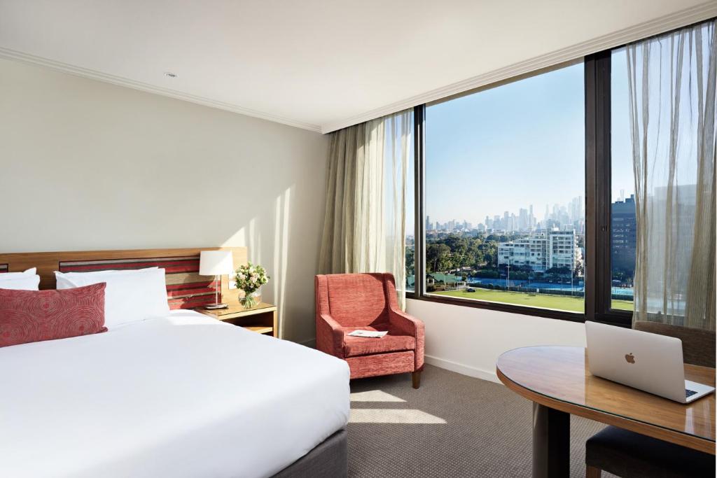 a hotel room with a bed and a desk with a laptop at View Melbourne in Melbourne