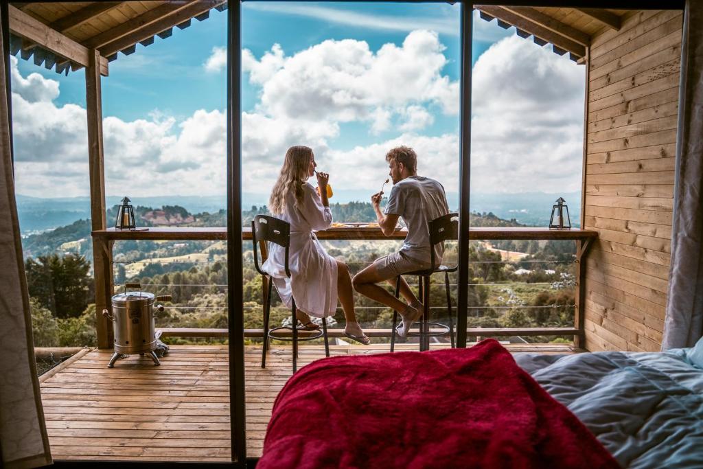 a man and a woman sitting at a table on a balcony at Caralsol Glamping in Rionegro