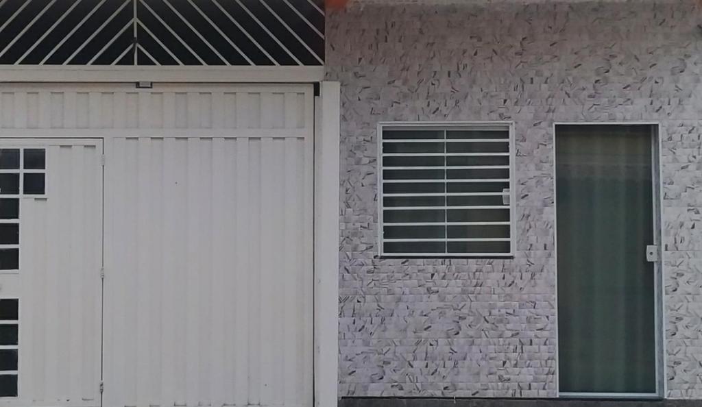 a house with a white garage door and a window at Flat familiar com ar,wi fi,cozinha e garagem in Aparecida
