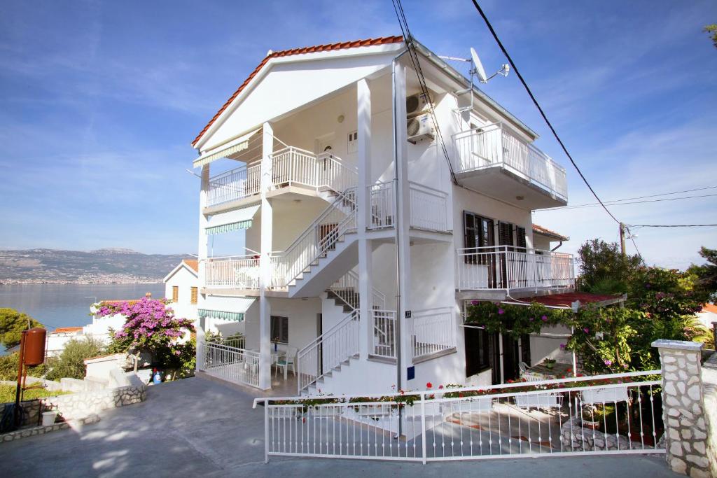 a white building with balconies and a body of water at Apartments by the sea Slatine, Ciovo - 972 in Trogir