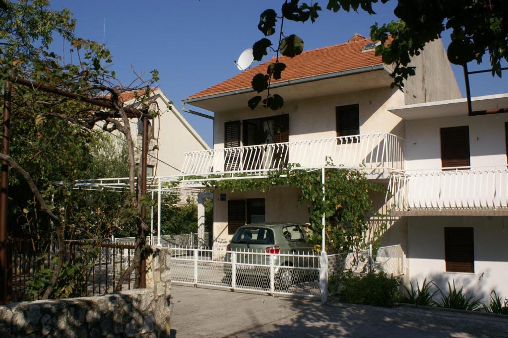 um edifício branco com um carro estacionado em frente em Apartments by the sea Seget Vranjica, Trogir - 1050 em Seget Vranjica