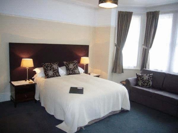 a bedroom with a large white bed and a couch at Buenos Aires Guest House in Bexhill