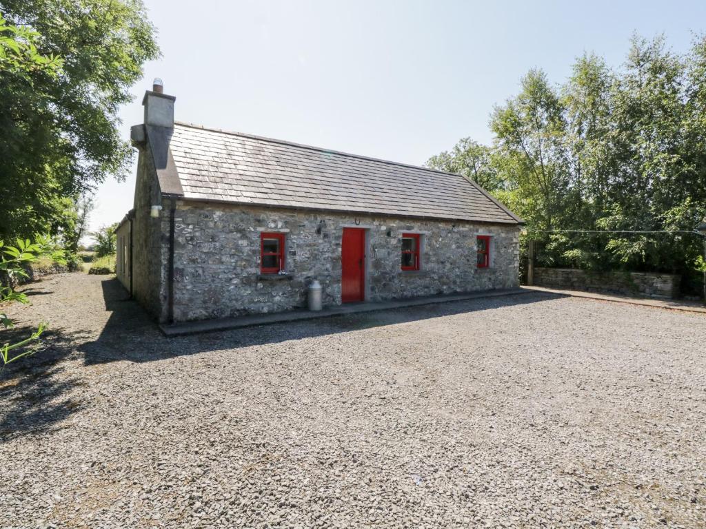a stone house with red doors and a gravel driveway at The Visiting House in Dunmore