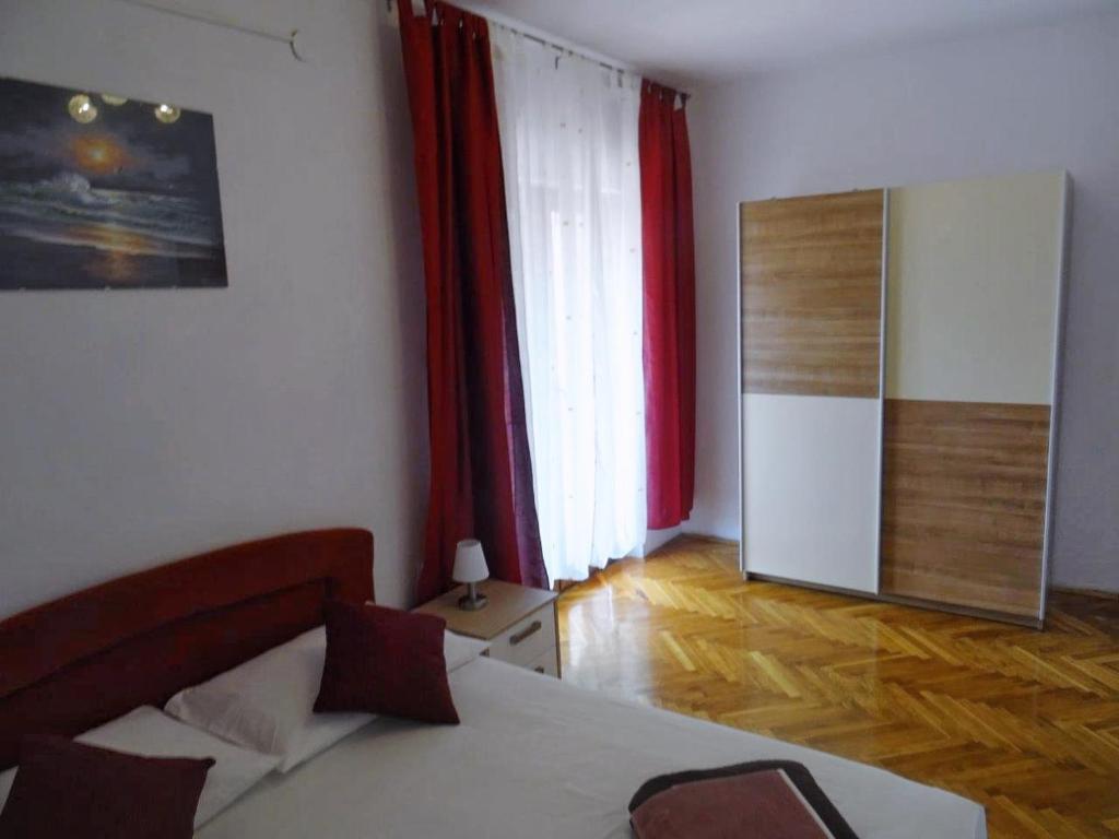 sypialnia z łóżkiem, czerwonymi zasłonami i lustrem w obiekcie Apartment Biograd na Moru 860b w Biogradzie na Moru