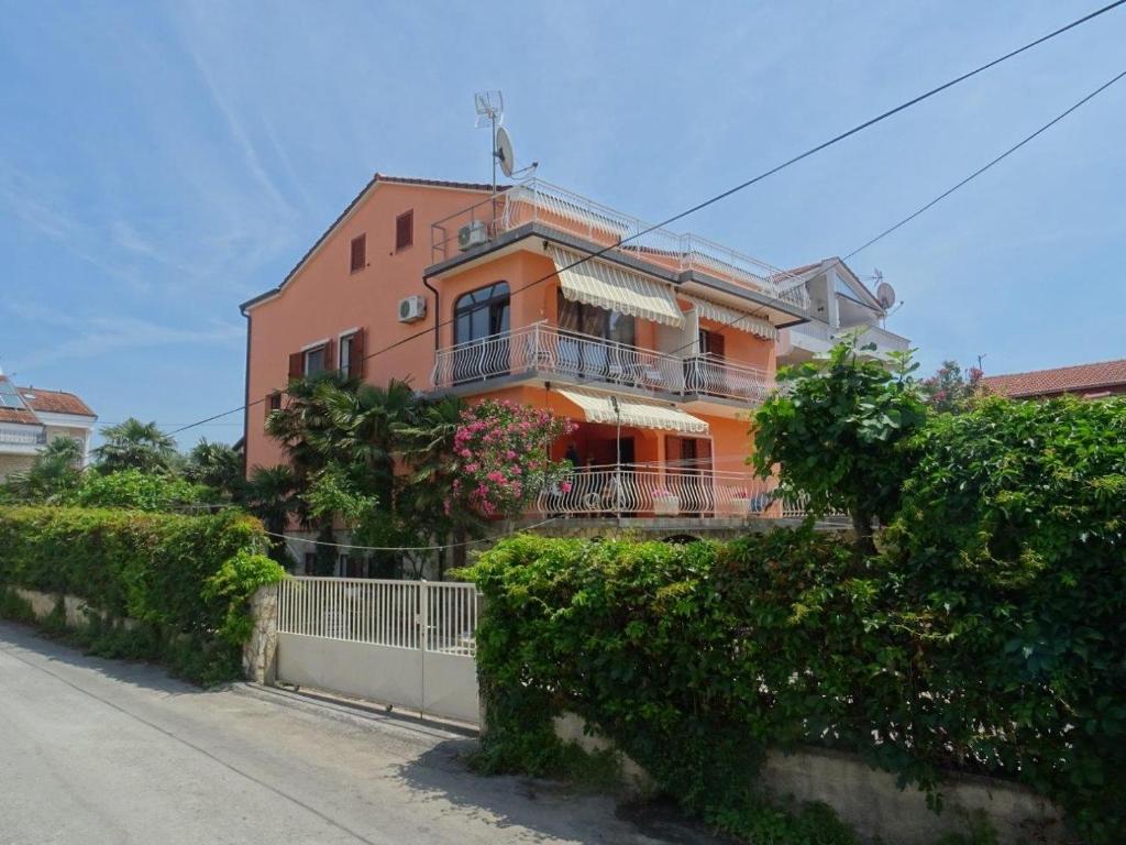 an orange house with a balcony on a street at Apartment Biograd na Moru 860c in Biograd na Moru