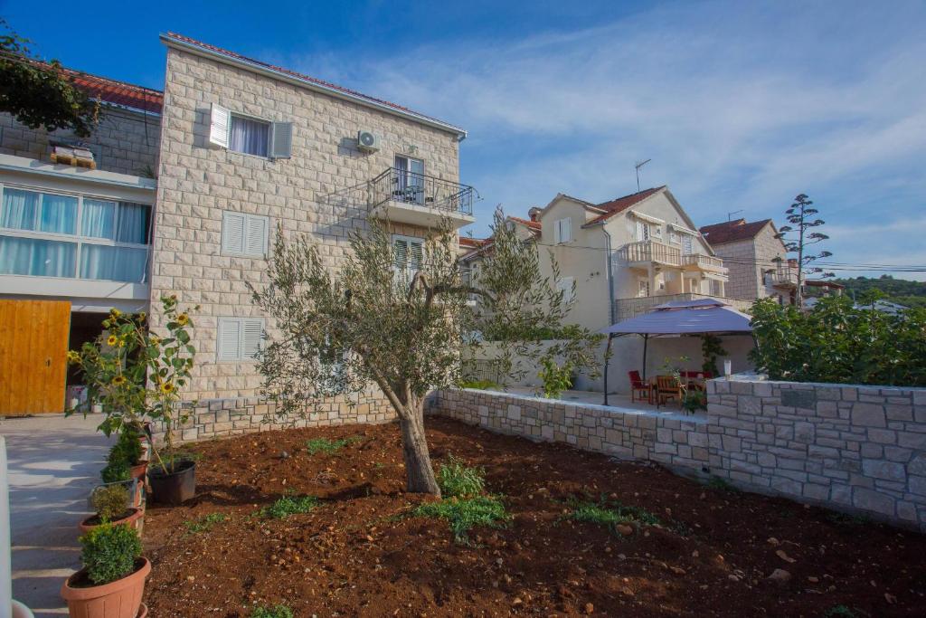 a house with a retaining wall and a tree in a yard at Apartments with a parking space Sutivan, Brac - 752 in Sutivan