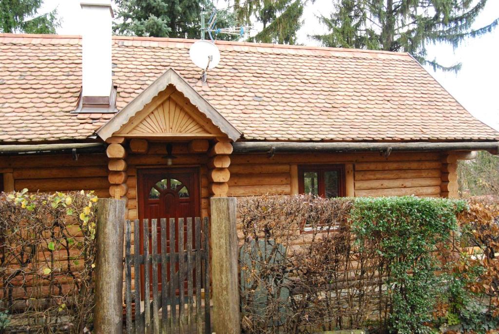 una baita di tronchi con una recinzione di fronte ad essa di Boróka Apartmanházak - Kakukk House a Velem