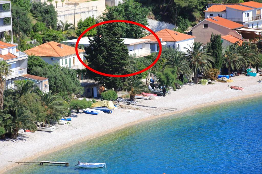 a red circle on a beach with houses and trees at Apartments by the sea Stanici, Omis - 1031 in Tice