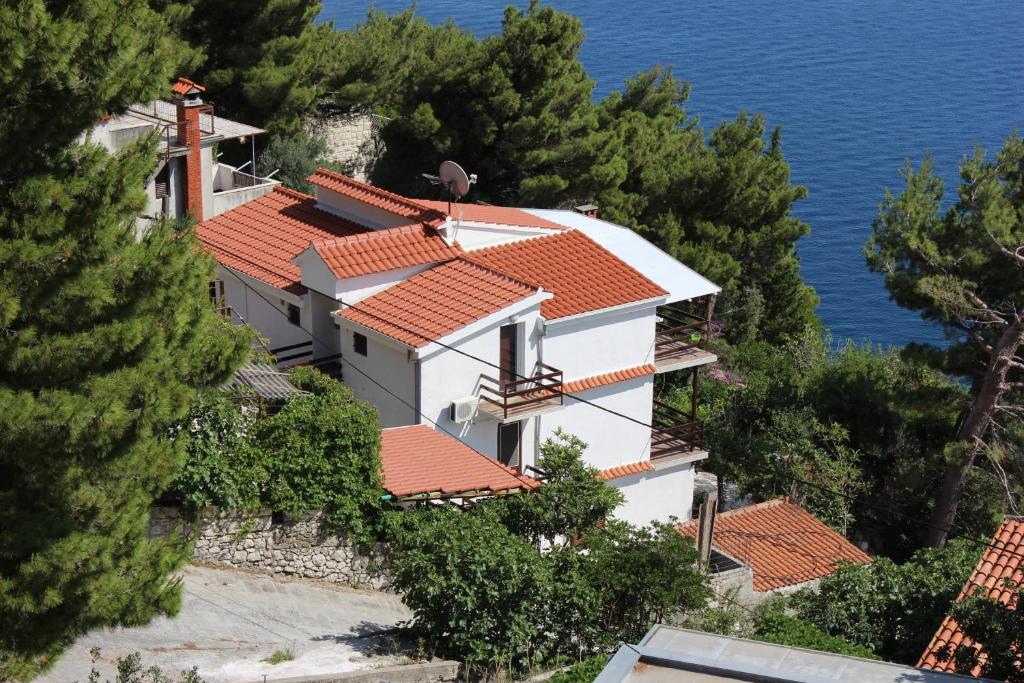 a house with red roofs on a hill with the ocean at Apartments by the sea Marusici, Omis - 1040 in Mimice