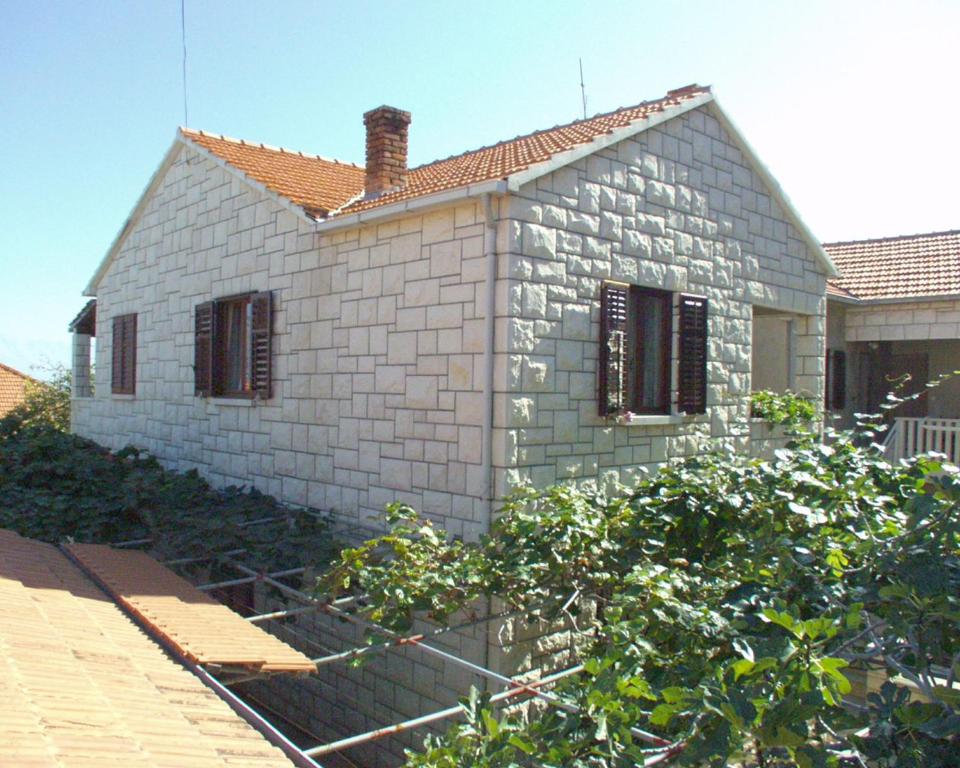 a small brick house with a garden in front of it at Apartments by the sea Postira, Brac - 738 in Postira